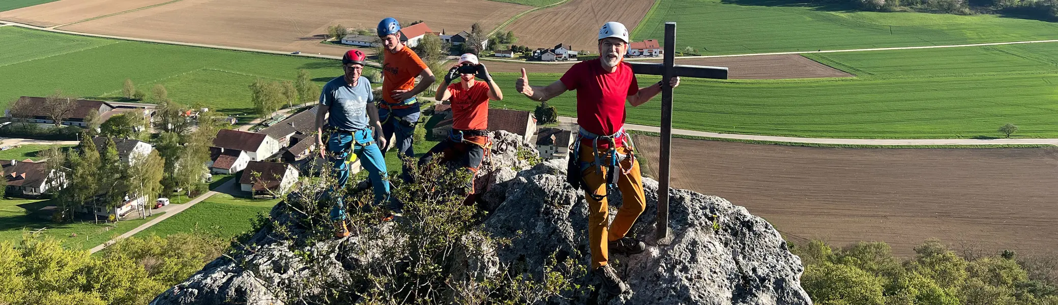 Gruppe von Menschen beim Klettern auf einem Fels mit Gipfelkreuz | © DAV Heilbronn