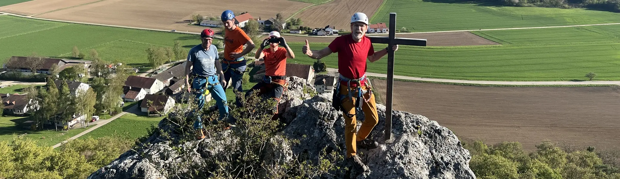 Gruppe von Menschen beim Klettern auf einem Fels mit Gipfelkreuz | © DAV Heilbronn