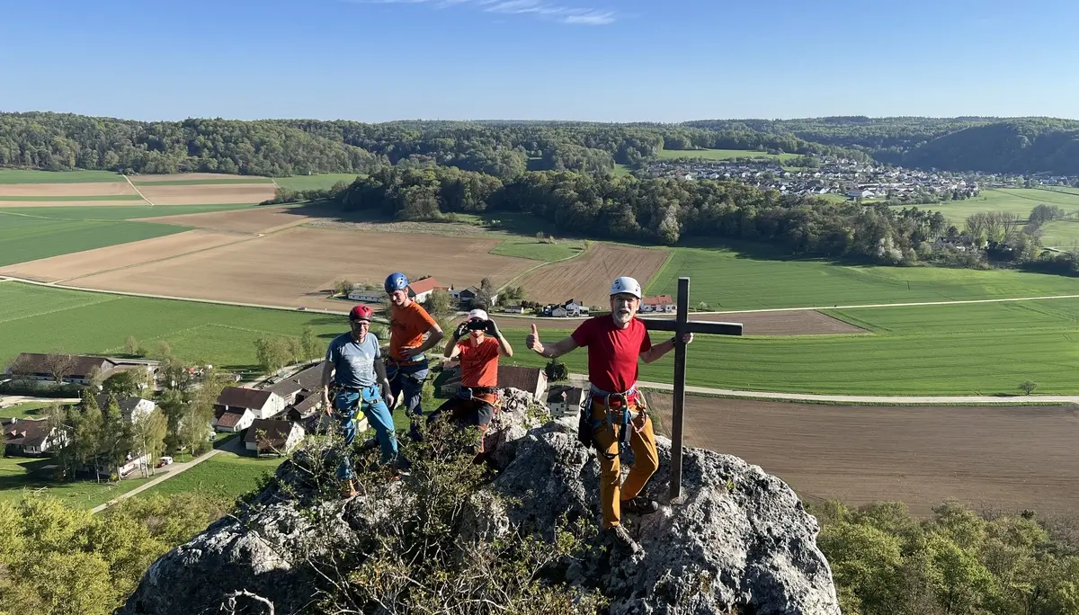 Gruppe von Menschen beim Klettern auf einem Fels mit Gipfelkreuz | © DAV Heilbronn