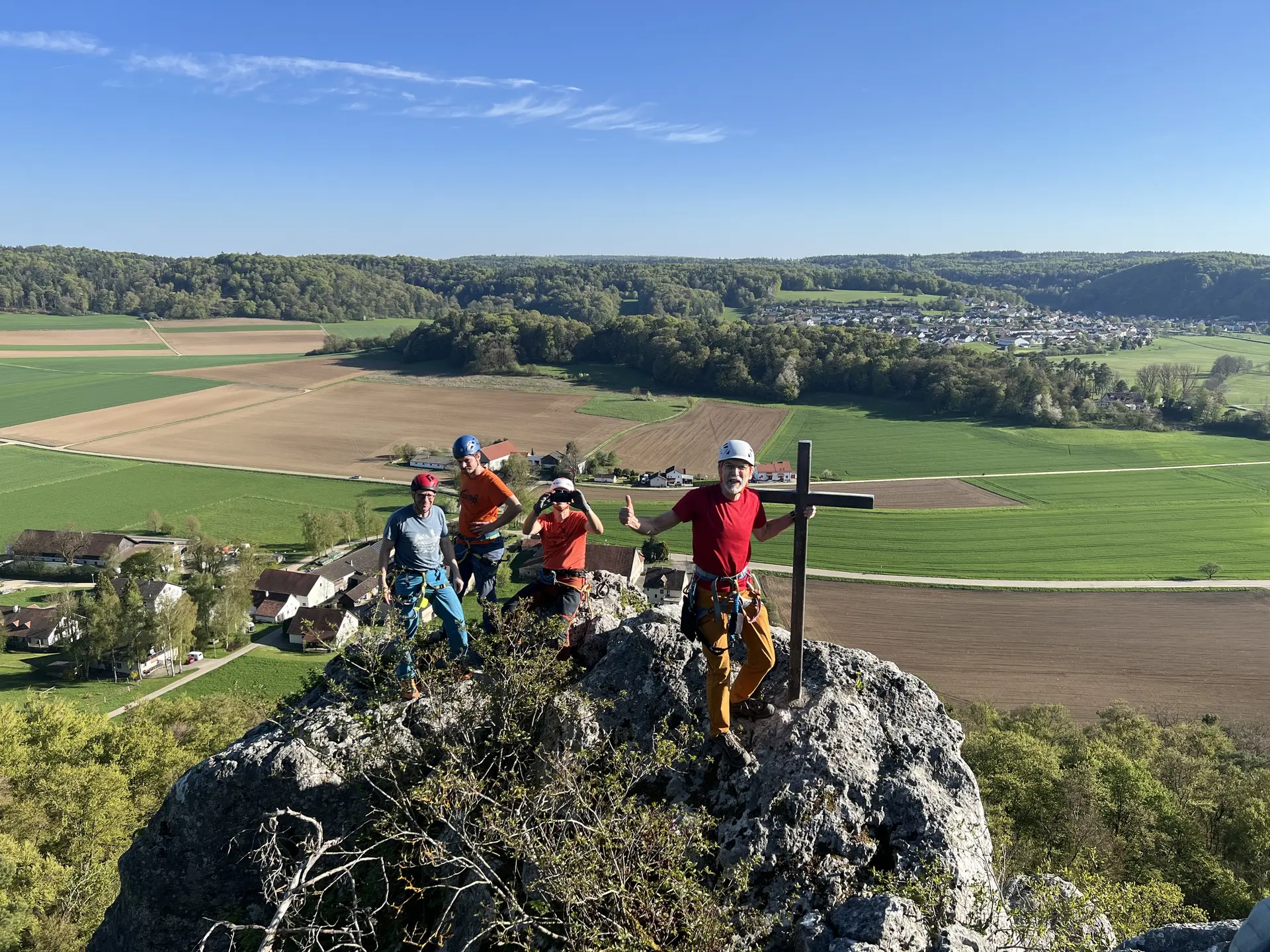 Gruppe von Menschen beim Klettern auf einem Fels mit Gipfelkreuz | © DAV Heilbronn