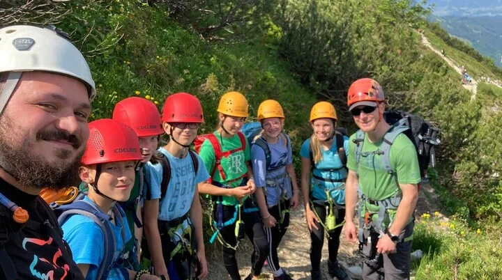 zwei Männer mit einer Kindergruppe beim Wandern an einem Steinpfad, umgeben von blühenden Pflanzen an einem Berg | © DAV Heilbronn BZG Öhringen