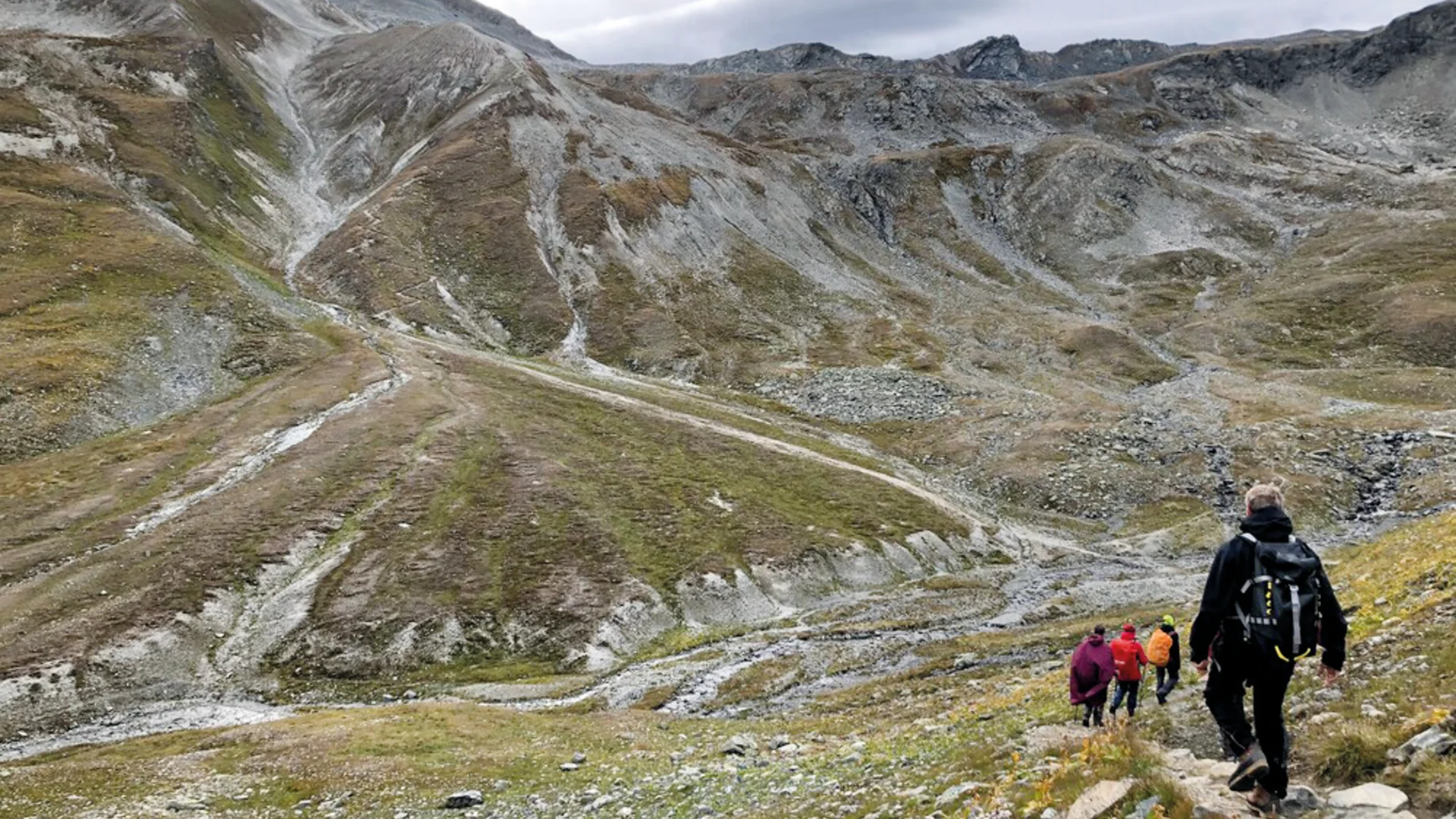 mehrere Wanderer laufen einen Pfad hinab in steiniger Landschaft, im Hintergrund Gebirge | © DAV Heilbronn