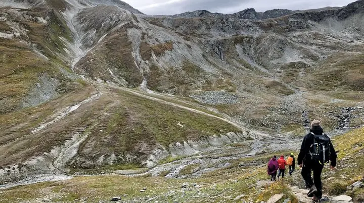 mehrere Wanderer laufen einen Pfad hinab in steiniger Landschaft, im Hintergrund Gebirge | © DAV Heilbronn