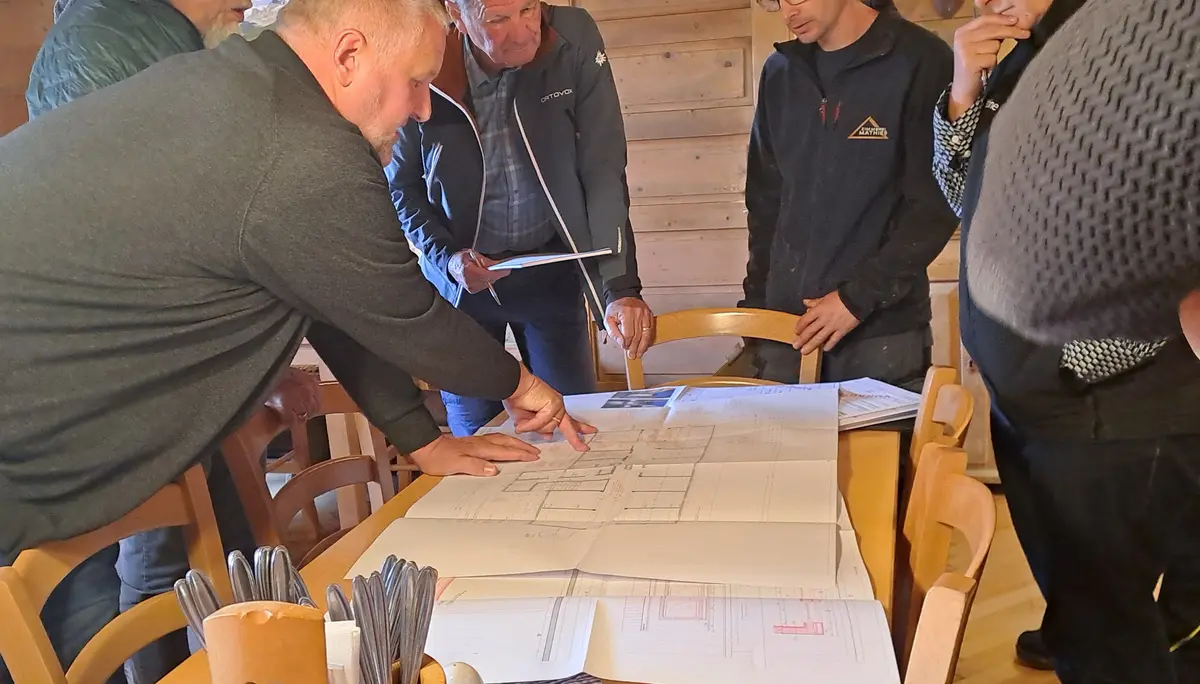 Neue Heilbronner Huette Innenansicht mit einer Gruppe von Menschen die einen Bauplan besprechen | © DAV Heilbronn