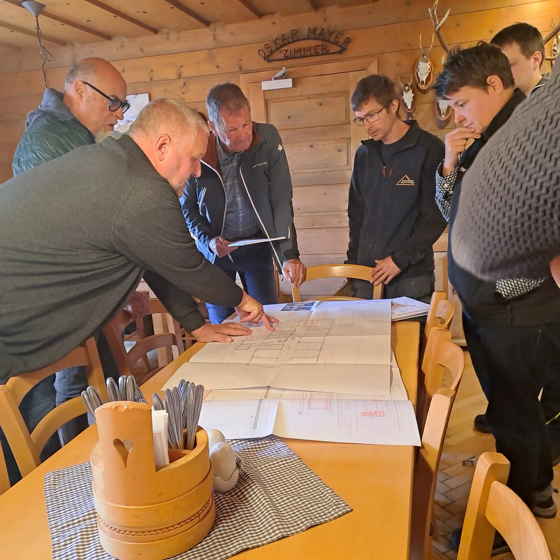 Neue Heilbronner Huette Innenansicht mit einer Gruppe von Menschen die einen Bauplan besprechen | © DAV Heilbronn