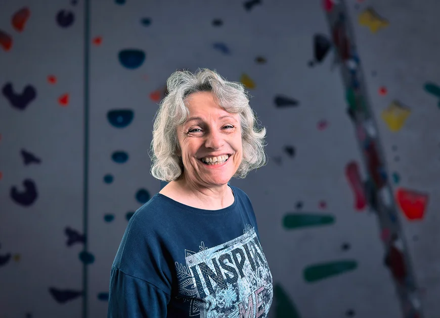 DAV Heilbronn Team | © DAV Heilbronn strahlende Frau mit schulterlangen, grauen Haaren und einem blauen Oberteil vor einer Kletterwand | © DAV Heilbronn