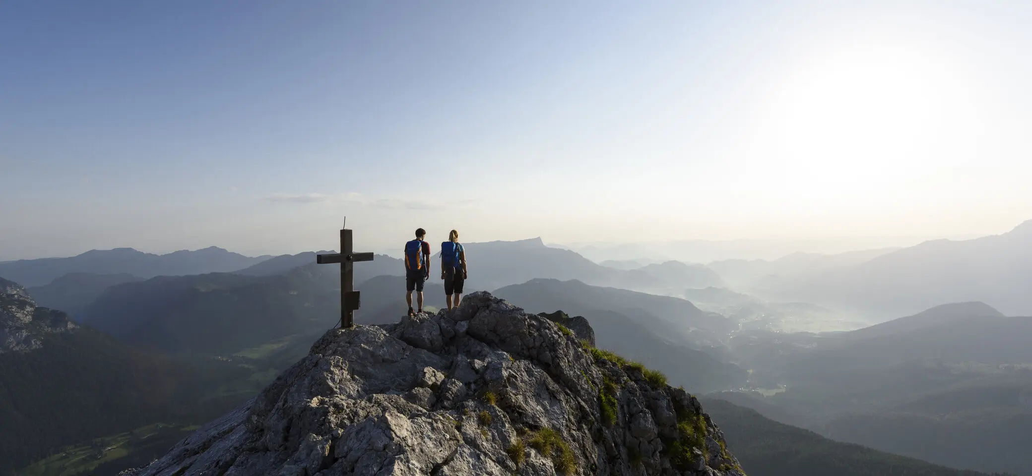 Zwei Wanderer auf einem Berggipfel mit Gipfelkreuz - aus der Ferne fotografiert | © DAV/Wolfgang Ehn