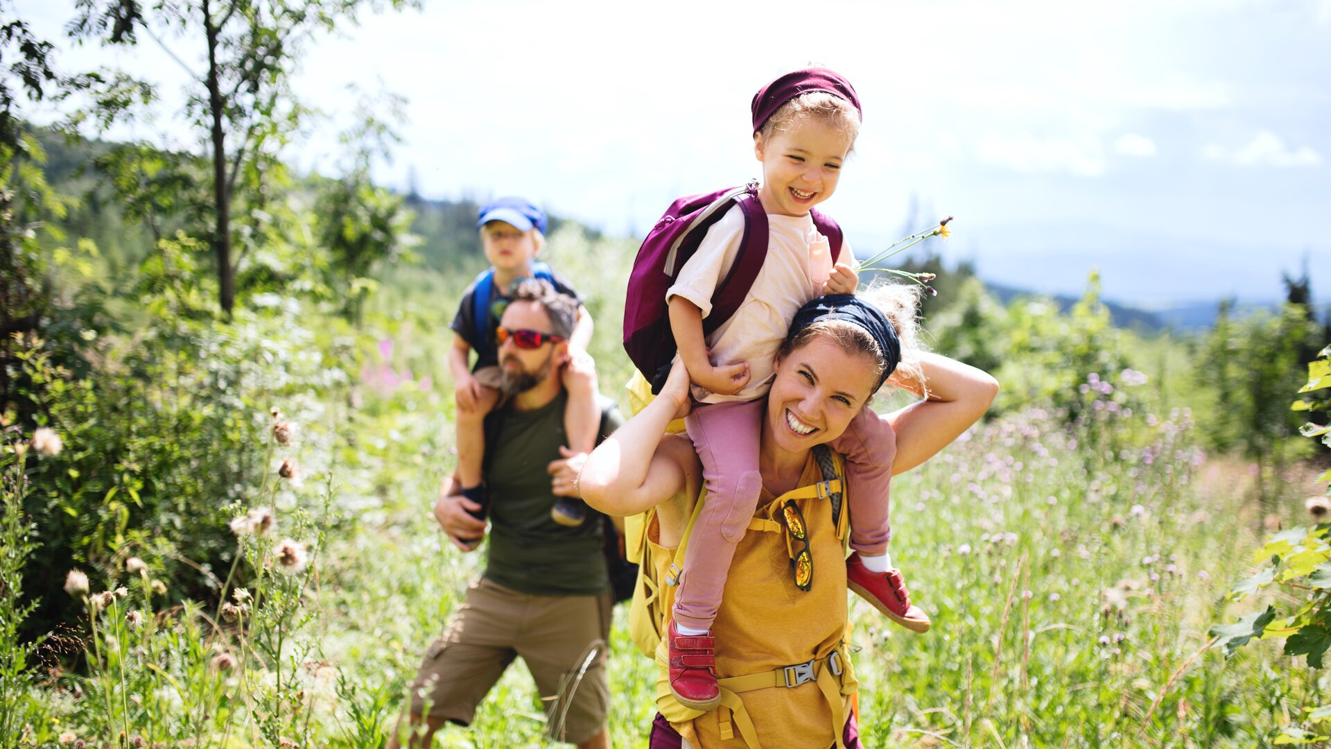 Raus ins echte Leben! | © Halfpoint / Adobe Stock Eine Familie in der Natur, die Mutter trägt ein Kind auf den Schultern | © Halfpoint / Adobe Stock